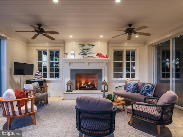 living room with a tile fireplace, crown molding, and ceiling fan