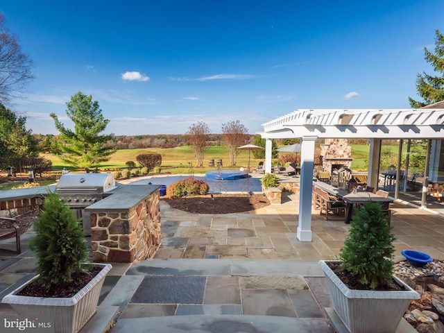 view of patio with a pergola, grilling area, an outdoor stone fireplace, and an outdoor kitchen