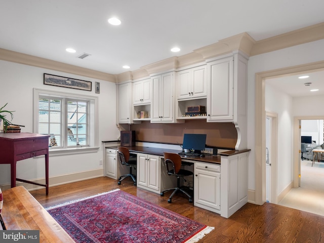 office area featuring built in desk, crown molding, and dark wood-type flooring