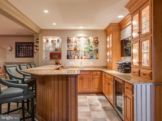 bar with light stone countertops, sink, and beverage cooler