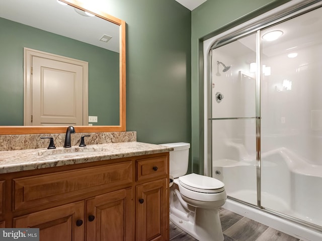 bathroom featuring hardwood / wood-style floors, vanity, an enclosed shower, and toilet