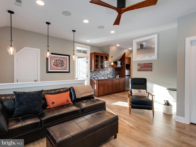 living room featuring light hardwood / wood-style floors, ceiling fan, and lofted ceiling