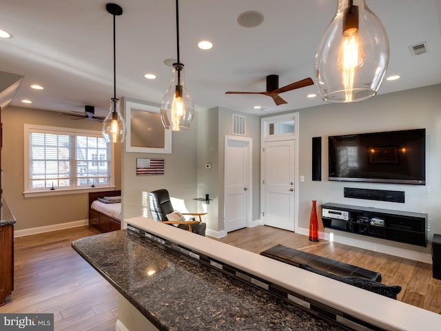 kitchen with hanging light fixtures, dark stone counters, and ceiling fan