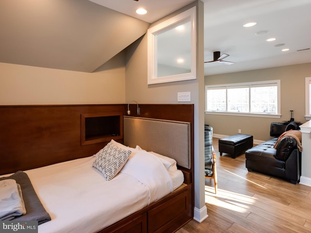 bedroom featuring light hardwood / wood-style floors, vaulted ceiling, and ceiling fan