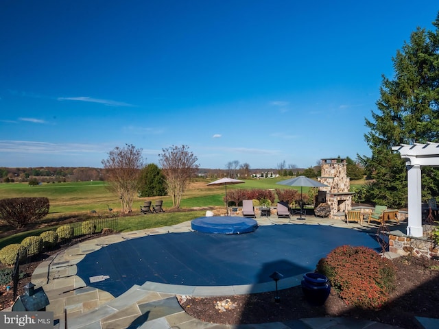 view of swimming pool featuring a patio area and an outdoor stone fireplace