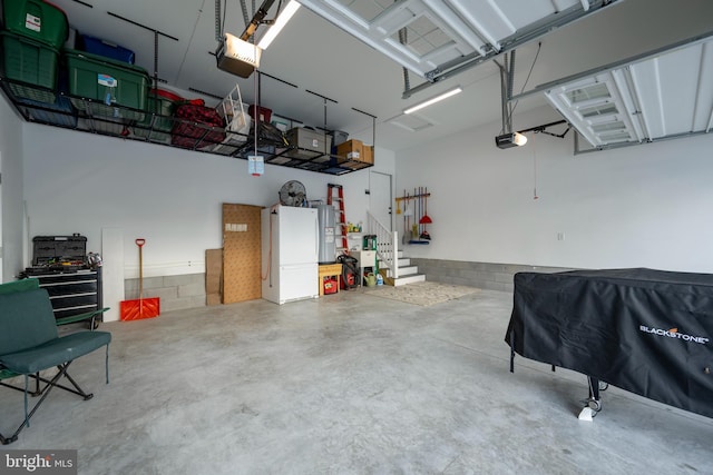 garage featuring electric water heater, white fridge, and a garage door opener