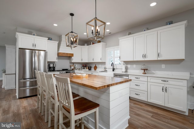 kitchen with custom range hood, stainless steel appliances, pendant lighting, a center island, and white cabinetry