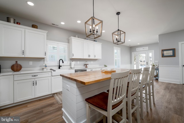 kitchen featuring wooden counters, sink, pendant lighting, white cabinets, and a center island