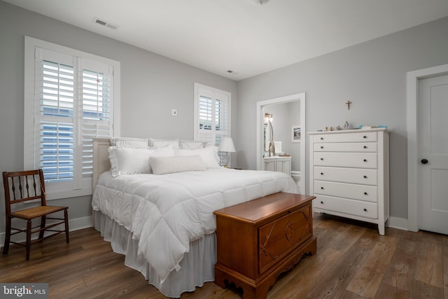 bedroom featuring connected bathroom, dark hardwood / wood-style floors, and multiple windows