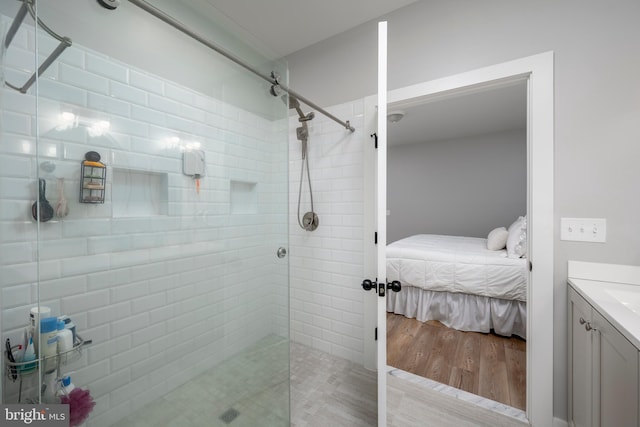 bathroom with hardwood / wood-style floors, vanity, and a shower with shower door