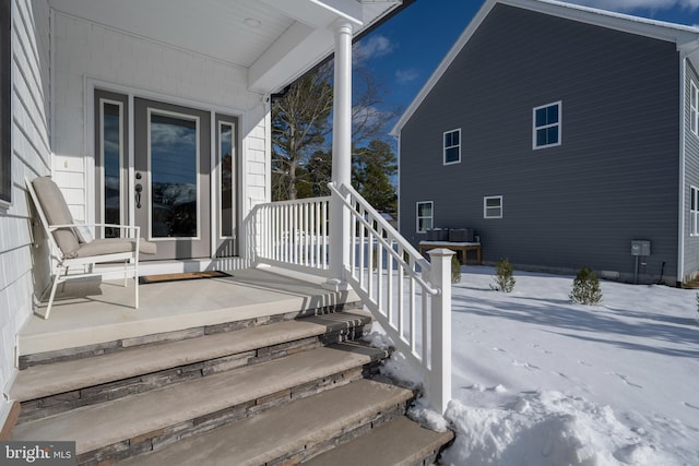 snow covered property entrance featuring a porch