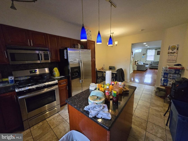 kitchen featuring appliances with stainless steel finishes, a center island, decorative light fixtures, and light tile patterned flooring