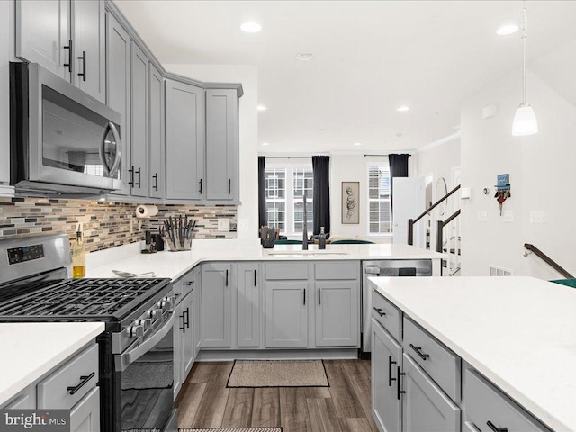 kitchen with decorative backsplash, gray cabinetry, stainless steel appliances, sink, and decorative light fixtures