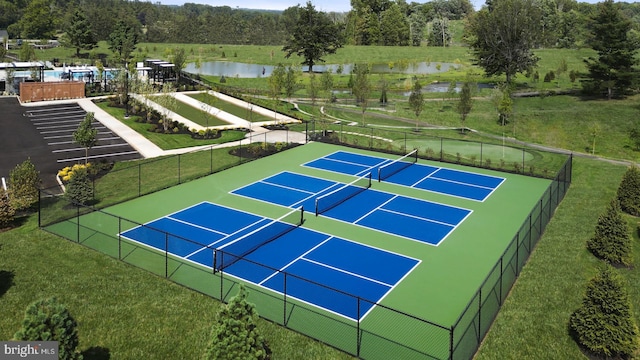 view of sport court with a yard and a water view