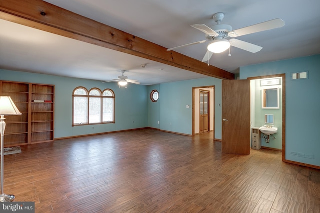 unfurnished living room with a ceiling fan, baseboards, wood finished floors, and beamed ceiling