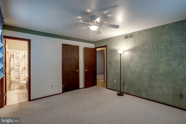 unfurnished bedroom featuring carpet floors, visible vents, connected bathroom, and a ceiling fan