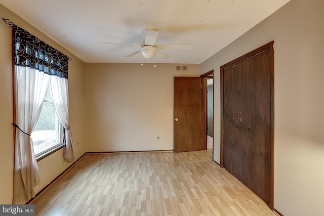 unfurnished bedroom featuring light wood finished floors, baseboards, visible vents, ceiling fan, and a closet