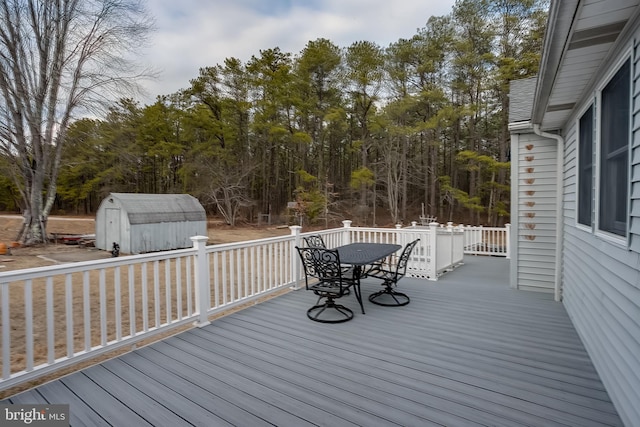 wooden deck with a storage shed, outdoor dining space, and an outdoor structure