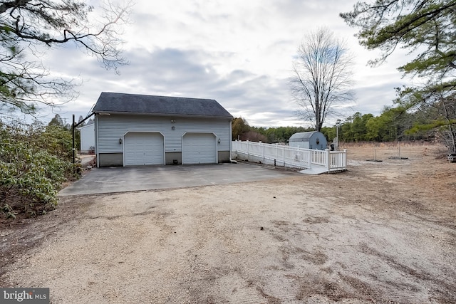 view of side of property with an outbuilding, a detached garage, and fence