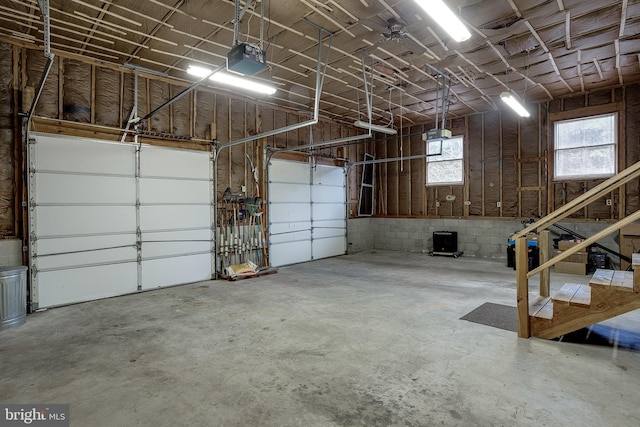 garage featuring concrete block wall and a garage door opener