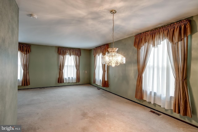 spare room with visible vents, carpet flooring, and an inviting chandelier