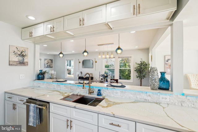 kitchen with light stone counters, decorative light fixtures, stainless steel dishwasher, a healthy amount of sunlight, and white cabinets