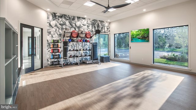 gym with ceiling fan, a drop ceiling, french doors, a towering ceiling, and wood-type flooring