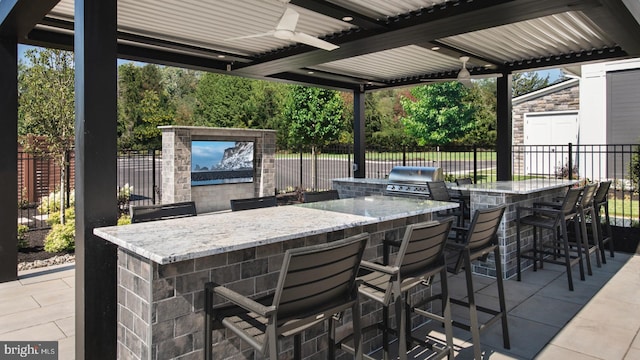 view of patio featuring area for grilling, ceiling fan, and an outdoor bar