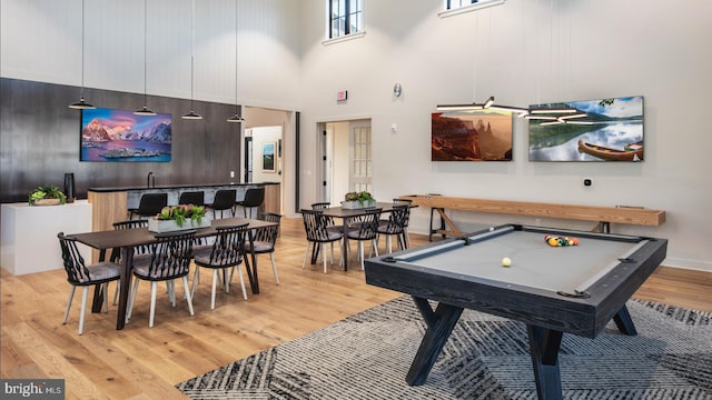 game room featuring bar, light hardwood / wood-style flooring, a towering ceiling, and billiards