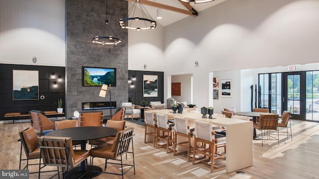 dining area featuring light wood-type flooring, beam ceiling, high vaulted ceiling, a notable chandelier, and a fireplace