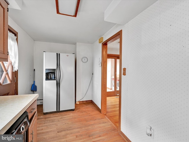 kitchen featuring white refrigerator with ice dispenser, light wood-type flooring, and black dishwasher