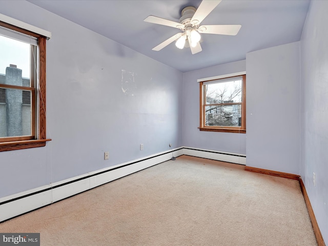 spare room with carpet flooring, ceiling fan, and a baseboard heating unit