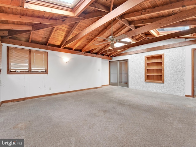 carpeted empty room featuring built in shelves, vaulted ceiling with skylight, and wood ceiling