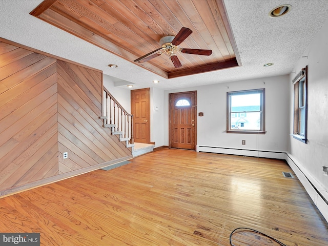 entryway featuring ceiling fan, a raised ceiling, light hardwood / wood-style floors, wooden walls, and wood ceiling