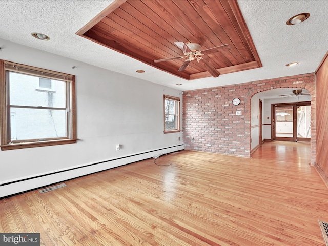 unfurnished living room featuring brick wall, a tray ceiling, baseboard heating, wooden ceiling, and light hardwood / wood-style floors