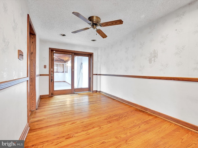 unfurnished room featuring ceiling fan, light hardwood / wood-style floors, and a textured ceiling