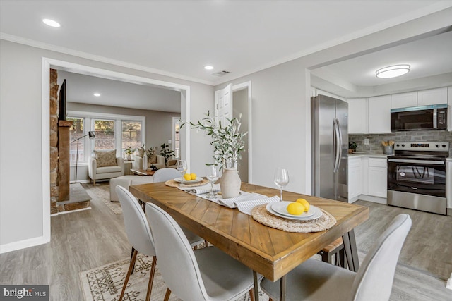 dining area featuring light wood-type flooring and ornamental molding