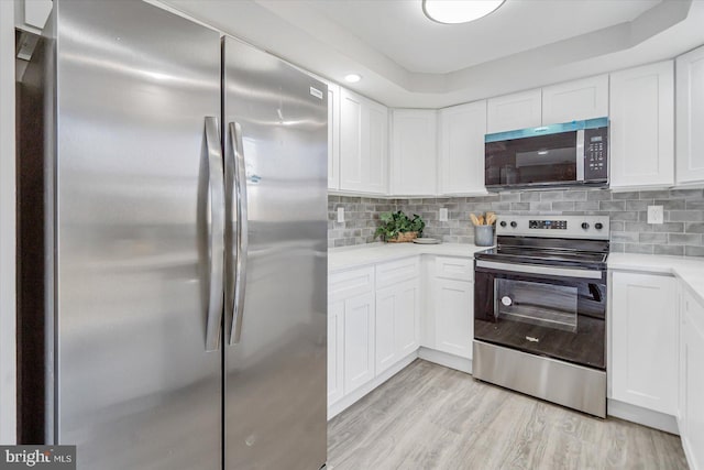 kitchen with white cabinets, backsplash, stainless steel appliances, and light hardwood / wood-style flooring