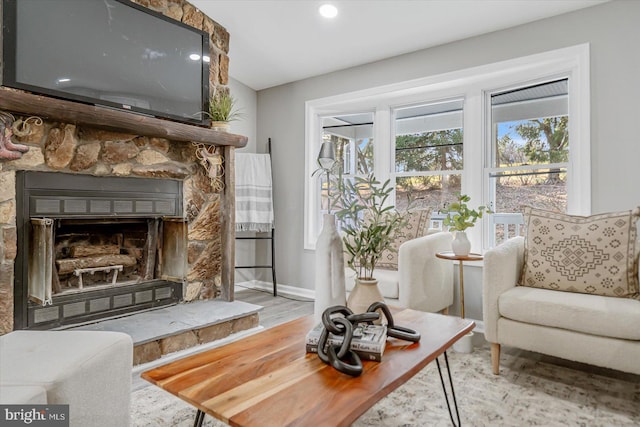 living area featuring light hardwood / wood-style floors and a stone fireplace