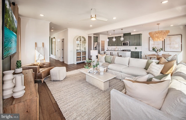 living room with dark wood-type flooring and ceiling fan with notable chandelier