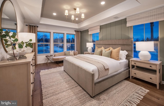 bedroom with a tray ceiling, crown molding, hardwood / wood-style floors, and a chandelier