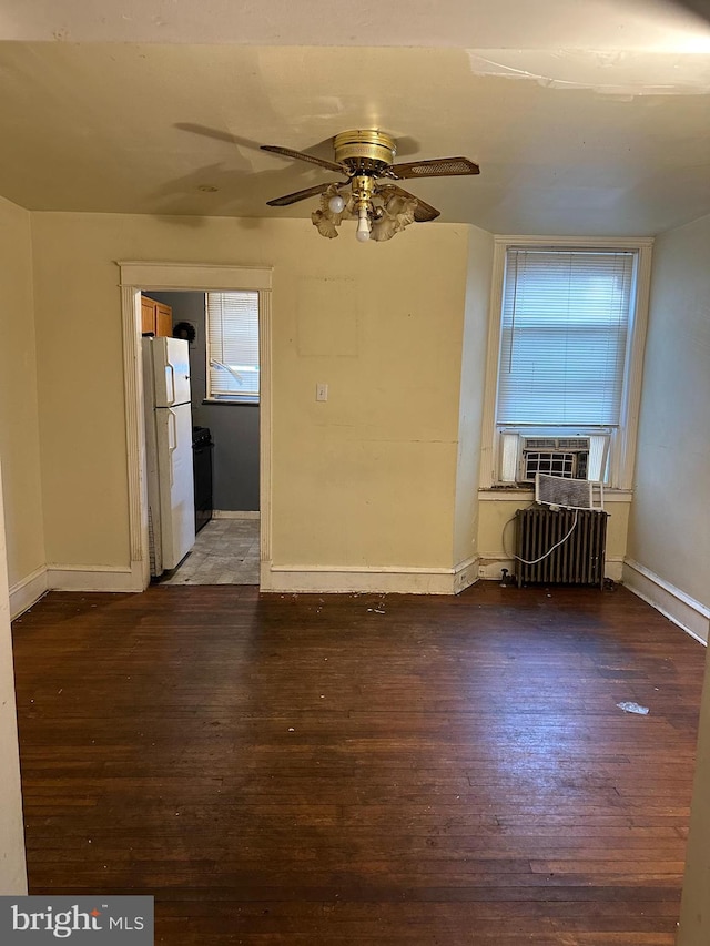 unfurnished room with dark hardwood / wood-style floors, radiator, cooling unit, and ceiling fan