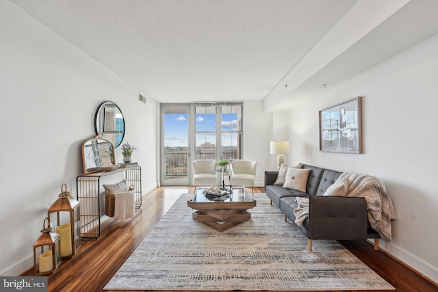 living room with a wall of windows, a textured ceiling, and dark wood-type flooring