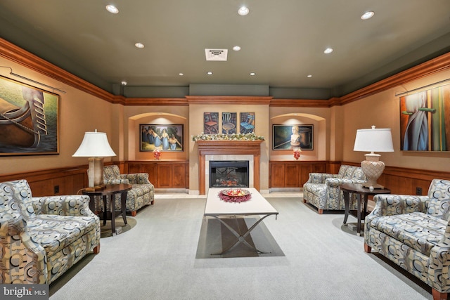 carpeted living room featuring ornamental molding and wood walls