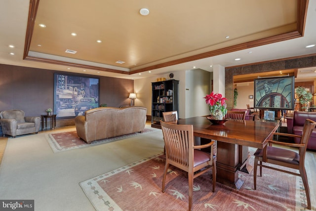 carpeted dining area with a tray ceiling and ornamental molding