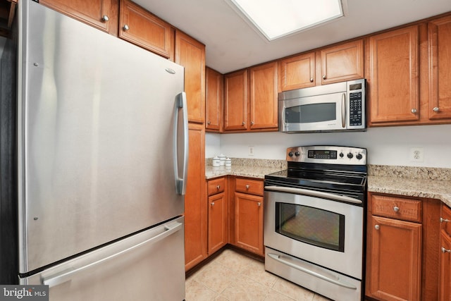 kitchen featuring light stone countertops, stainless steel appliances, and light tile patterned floors