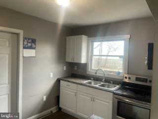 kitchen featuring range, white cabinetry, and sink