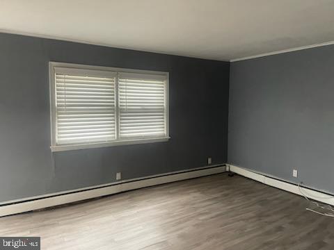 spare room featuring hardwood / wood-style flooring and a baseboard heating unit