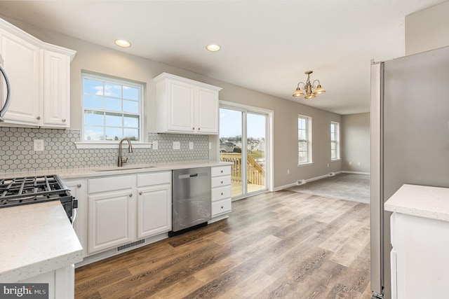 kitchen featuring white cabinets, sink, stainless steel appliances, and pendant lighting