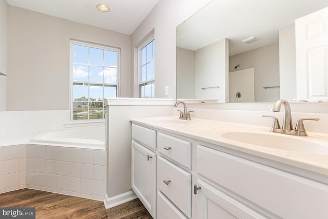 bathroom with tiled tub, hardwood / wood-style floors, and vanity